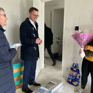 Bewoner ontvangt bloemen van directeur Cees Tip in haar nieuwbouw appartement