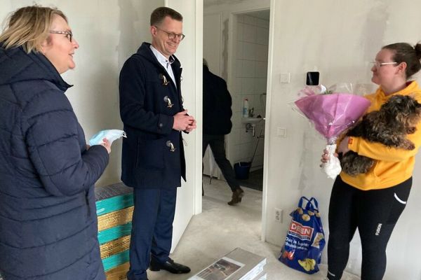 Bewoner ontvangt bloemen van directeur Cees Tip in haar nieuwbouw appartement