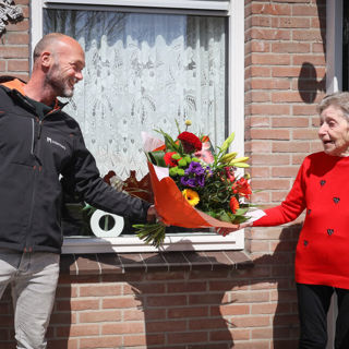 Bewoner ontvangt een bos bloemen van een medewerker van Intermaris
