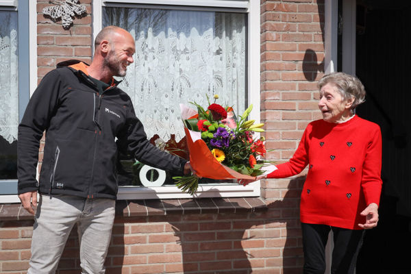Bewoner ontvangt een bos bloemen van een medewerker van Intermaris