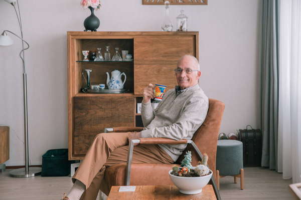 Oudere man drinkt een kop koffie in de stoel