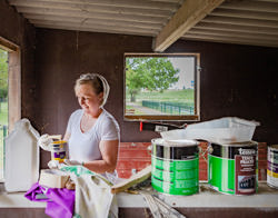 Vrouw staat in een schuur met potten beits