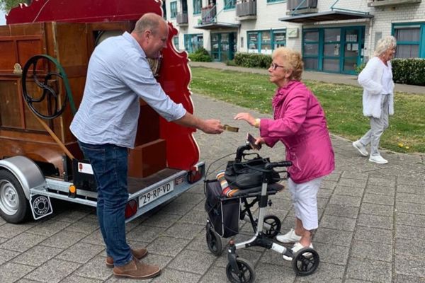 Bewoonster met rollator geeft geld aan de man van de draaiorgel