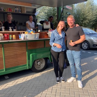 Bewoners staan bij een eetkraam voor het woongebouw