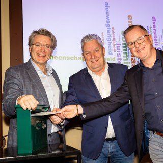 Drie mannen stoppen een brief in een brievenbus