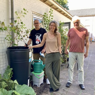 Drie bewoners poseren bij regenton