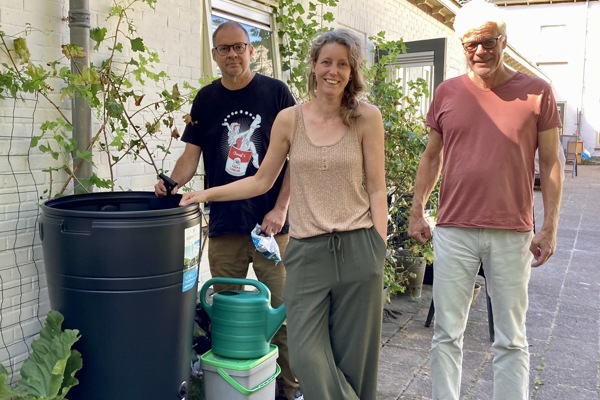 Drie bewoners poseren bij regenton