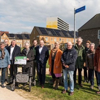 Meerdere bewoners staan op een rij buiten in de wijk