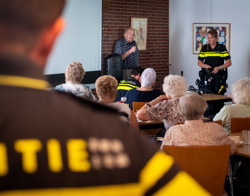 Bewoner en politie leggen aan andere bewoners uit over babbeltrucs 