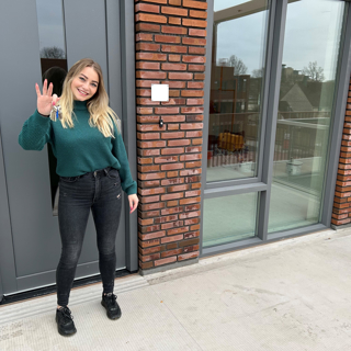 Bewoonster staat voor haar nieuwe woning met de sleutel in haar hand