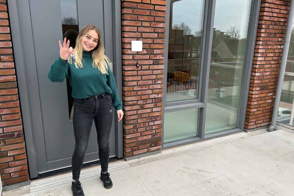 Bewoonster staat voor haar nieuwe woning met de sleutel in haar hand