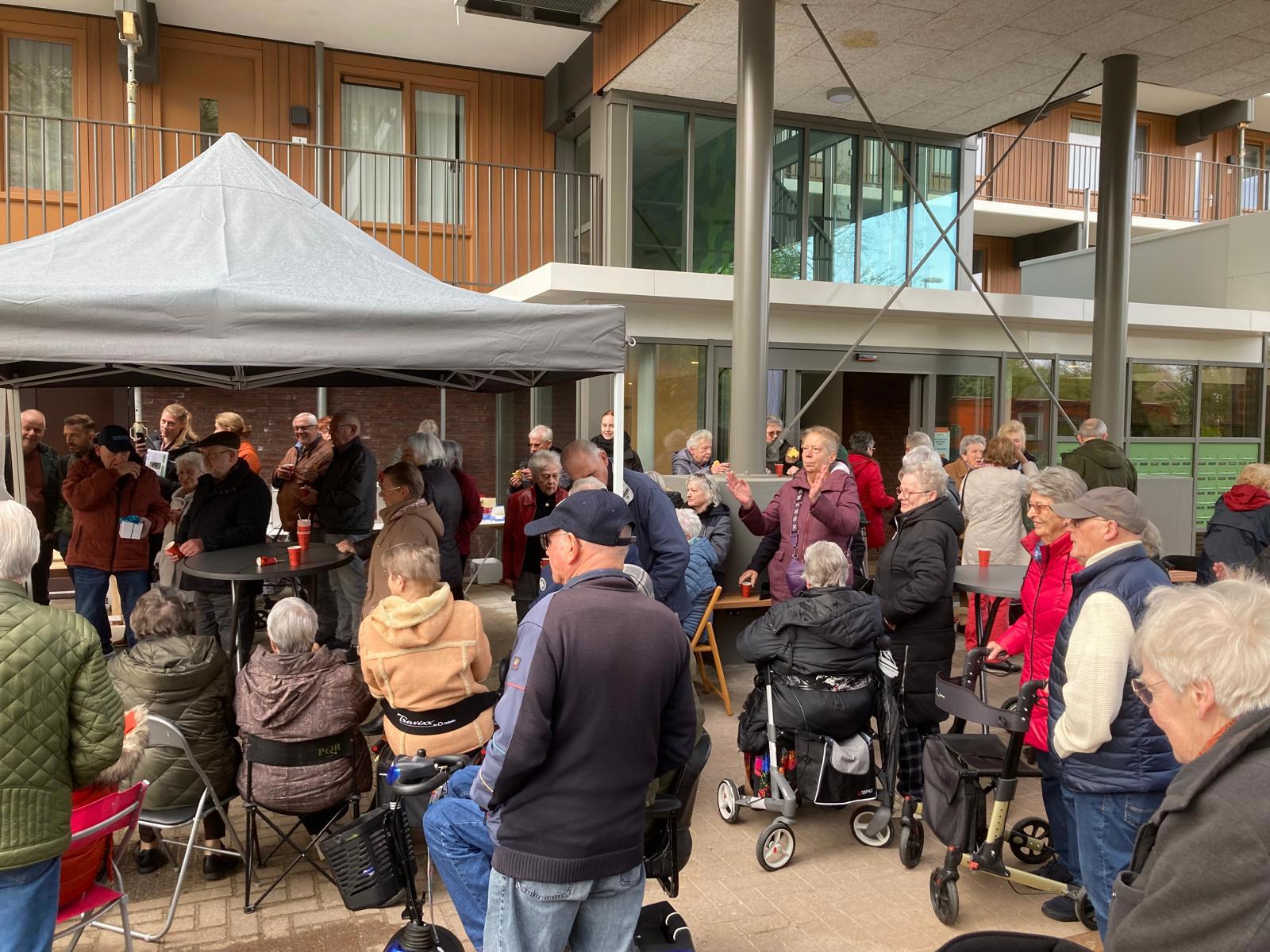 Verschillende bewoners zijn aanwezig bij de opening van een woongebouw 