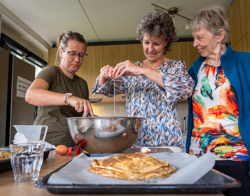 Medewerkers Intermaris bakken pannenkoeken met bewoner van Philadelphia Zorg