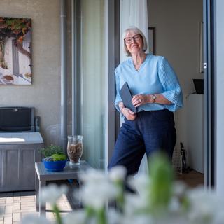 Mevrouw Van der Weide poseert met iPad in hand op haar balkon