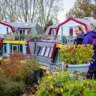 Twee bewoonsters staan op een balkon met plantenbakken