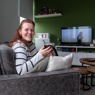 Bewoonster Broekerhof zit in haar woonkamer op de bank