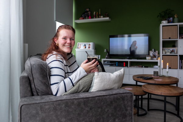 Bewoonster Broekerhof zit in haar woonkamer op de bank