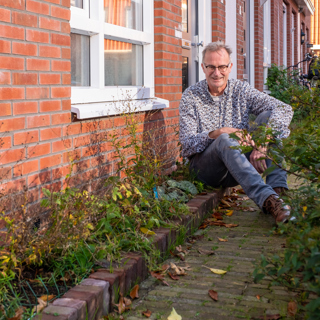 Bewoner Jos zit voor zijn geveltuintje