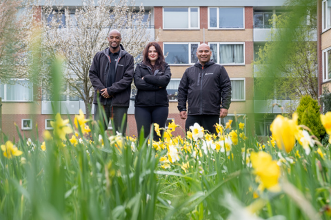 Drie medewerkers van buurtteam Purmerend Oost staan voor een woongebouw