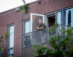 Bewoner staat op zijn balkon naar buiten te kijken