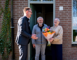 Directeur Cees tip geeft bloemen aan bewoners